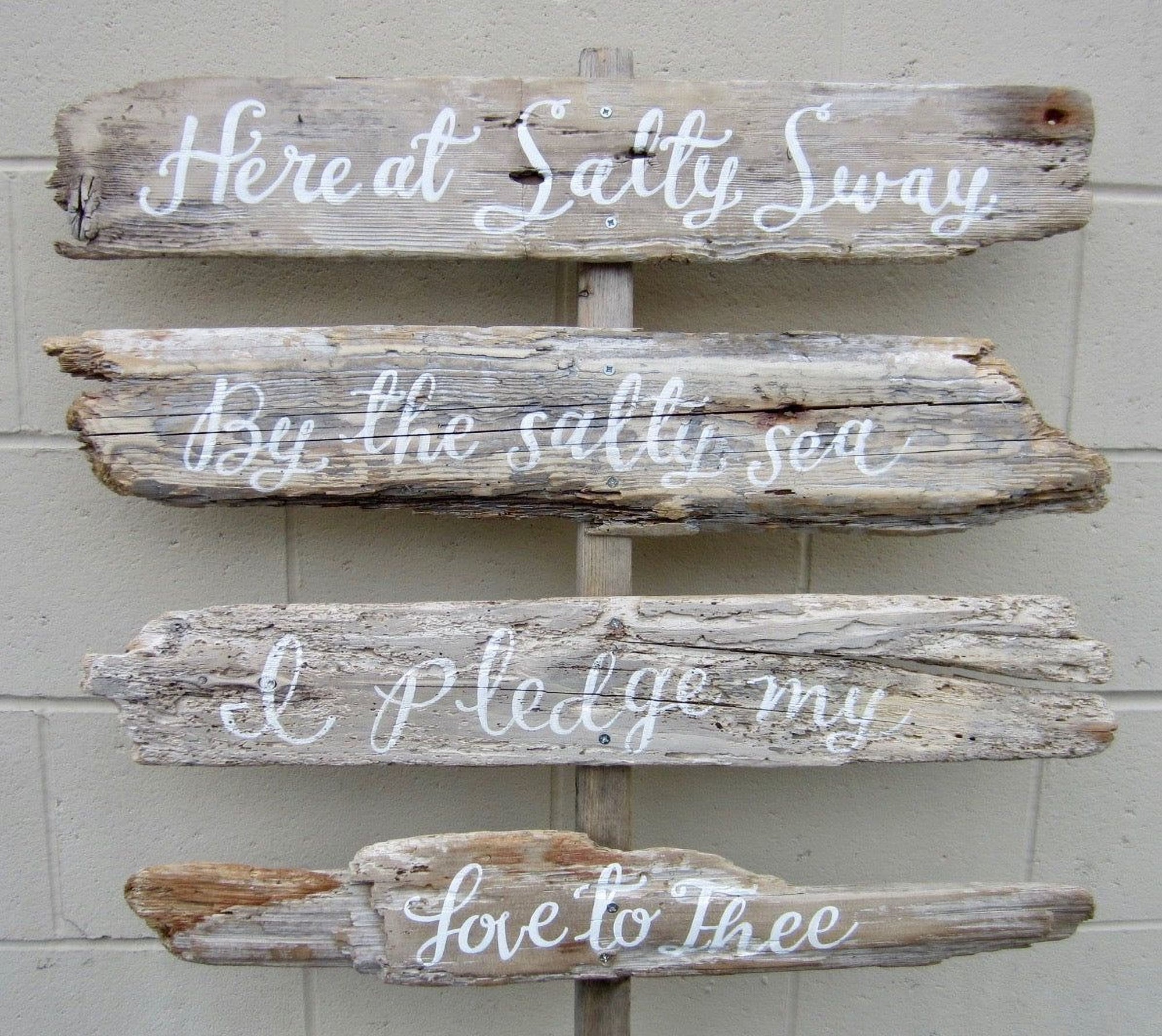 a wooden sign with a message about the sea, attached to a wall.