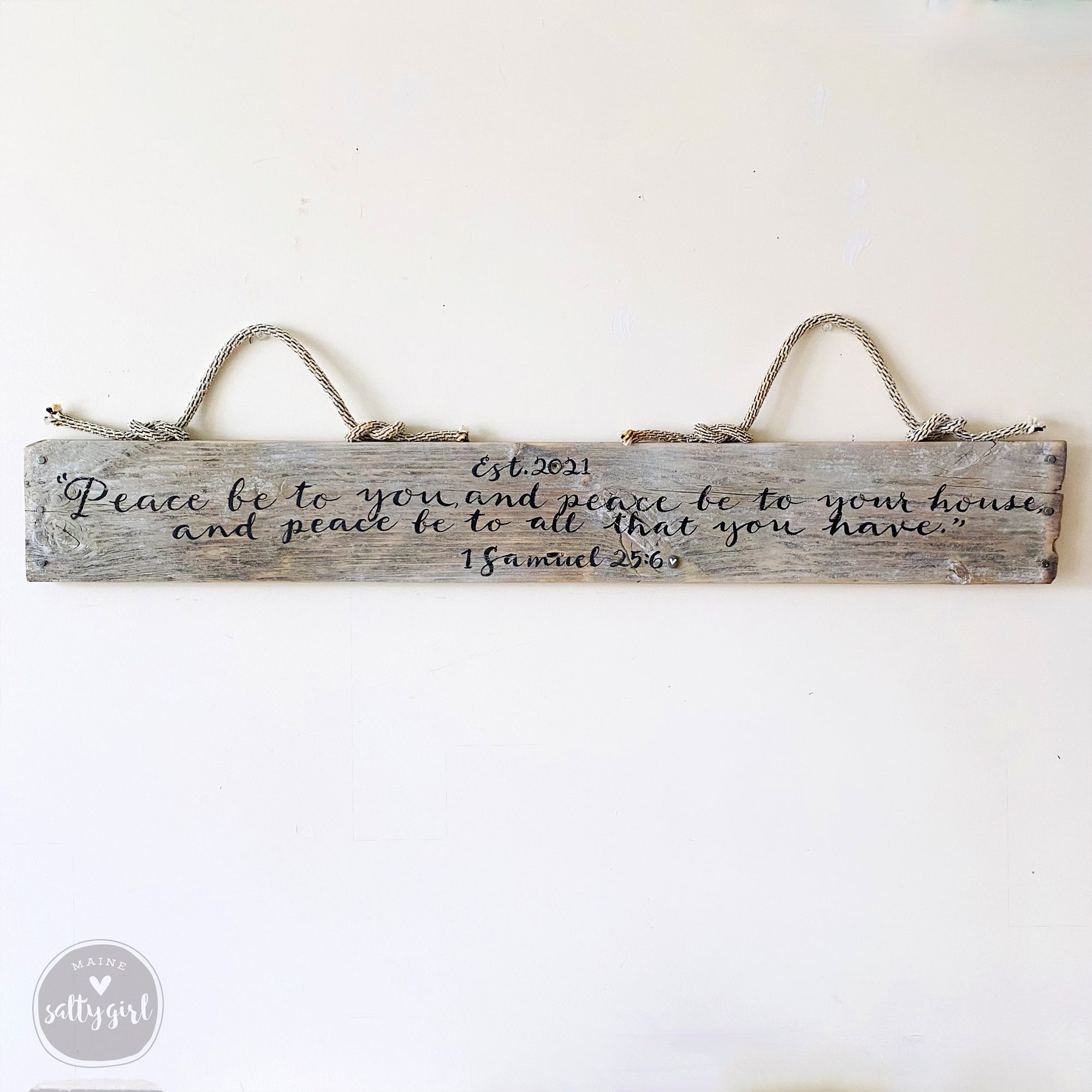 a wooden sign with a message about peace and love, hanging on a wall.