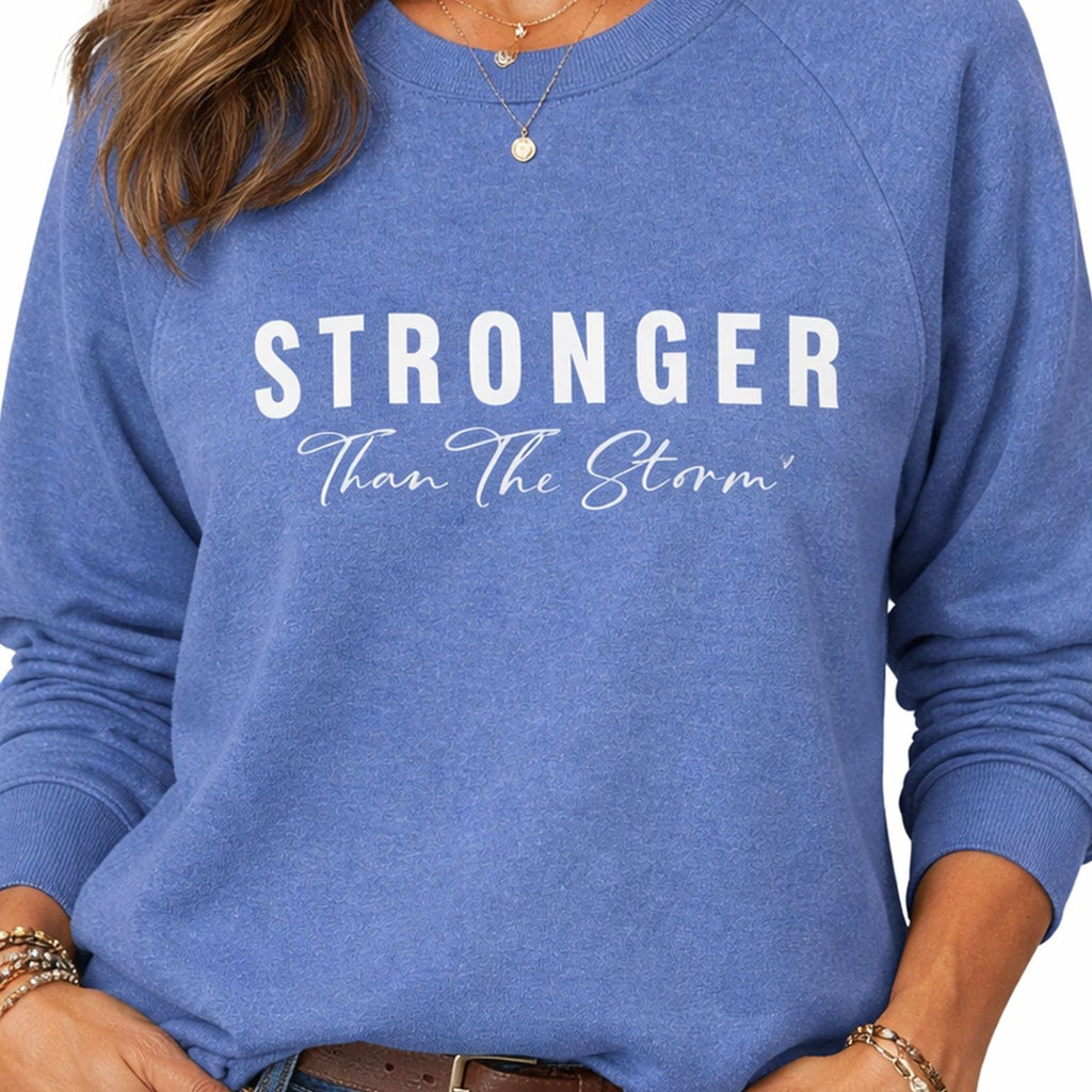 A woman wearing a blue Maine Salty Girl sweatshirt with the text "STRONGER Than The Storm" printed on it.