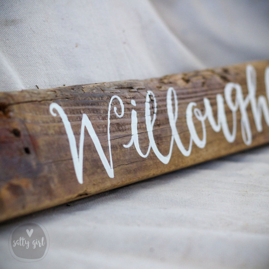 A close-up image of a wooden sign with the word "Willoughton" written on it in a cursive font.