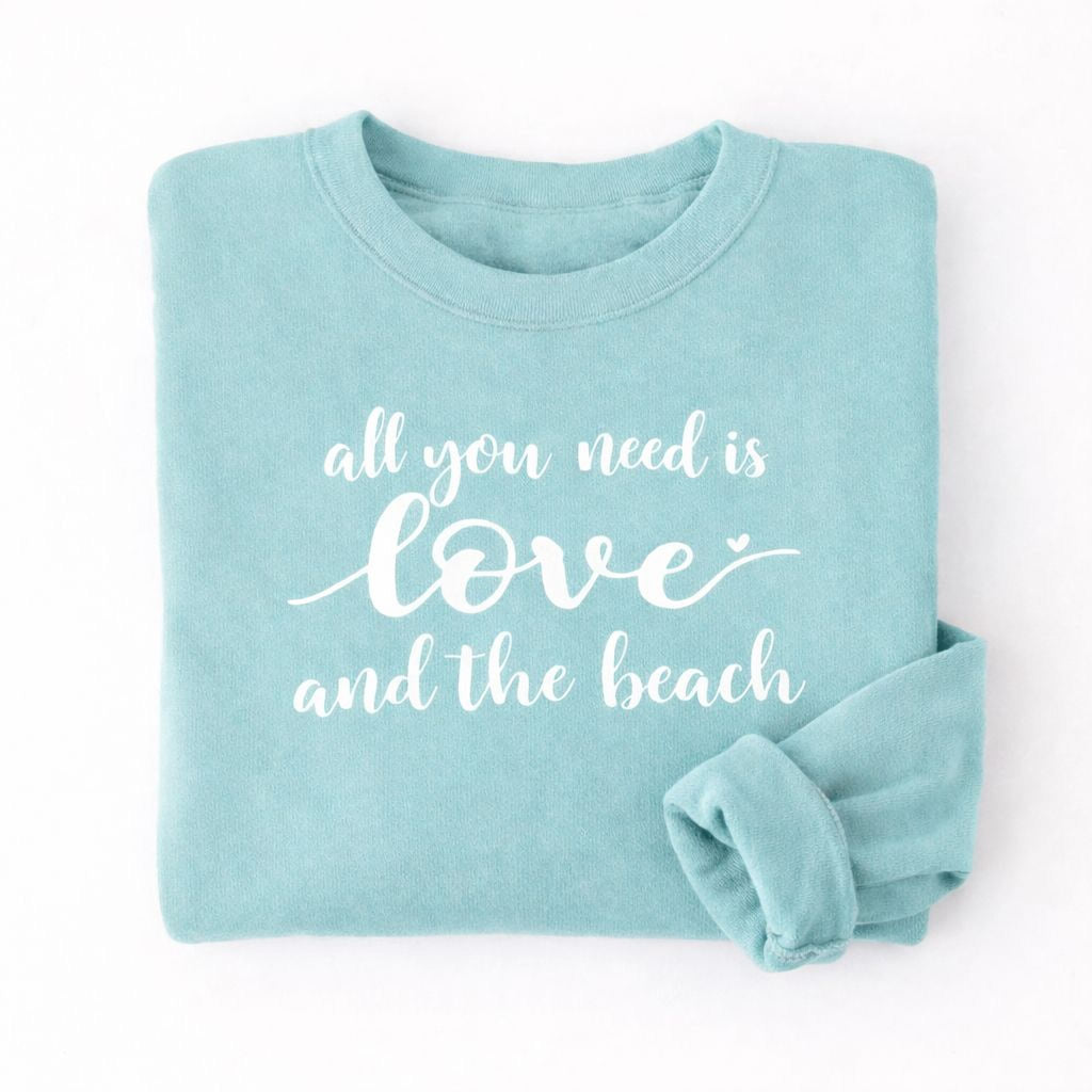 A light blue Maine Salty Girl sweatshirt with the text "all you need is love and the beach" printed on it.