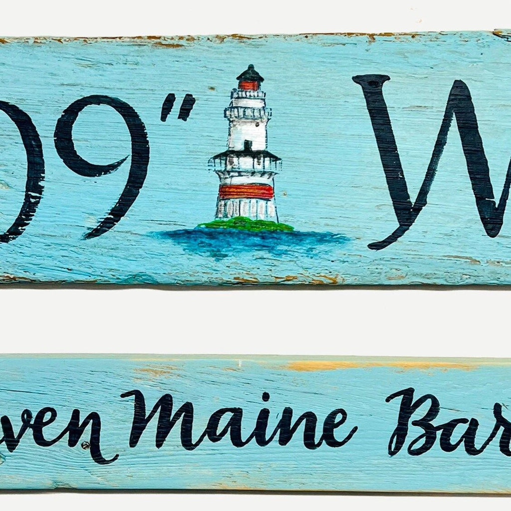 a wooden sign with a lighthouse painted on it.