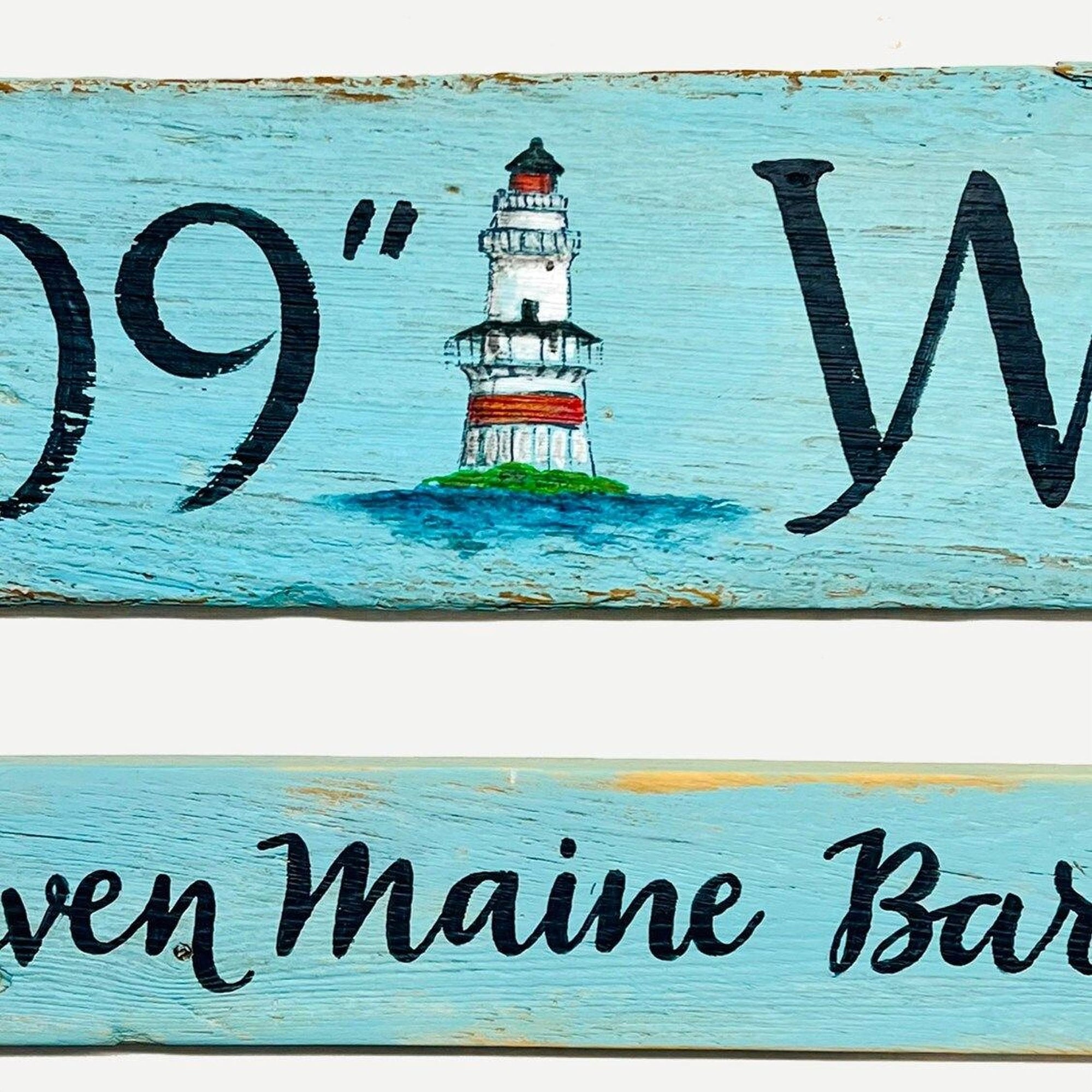 a wooden sign with a lighthouse painted on it.