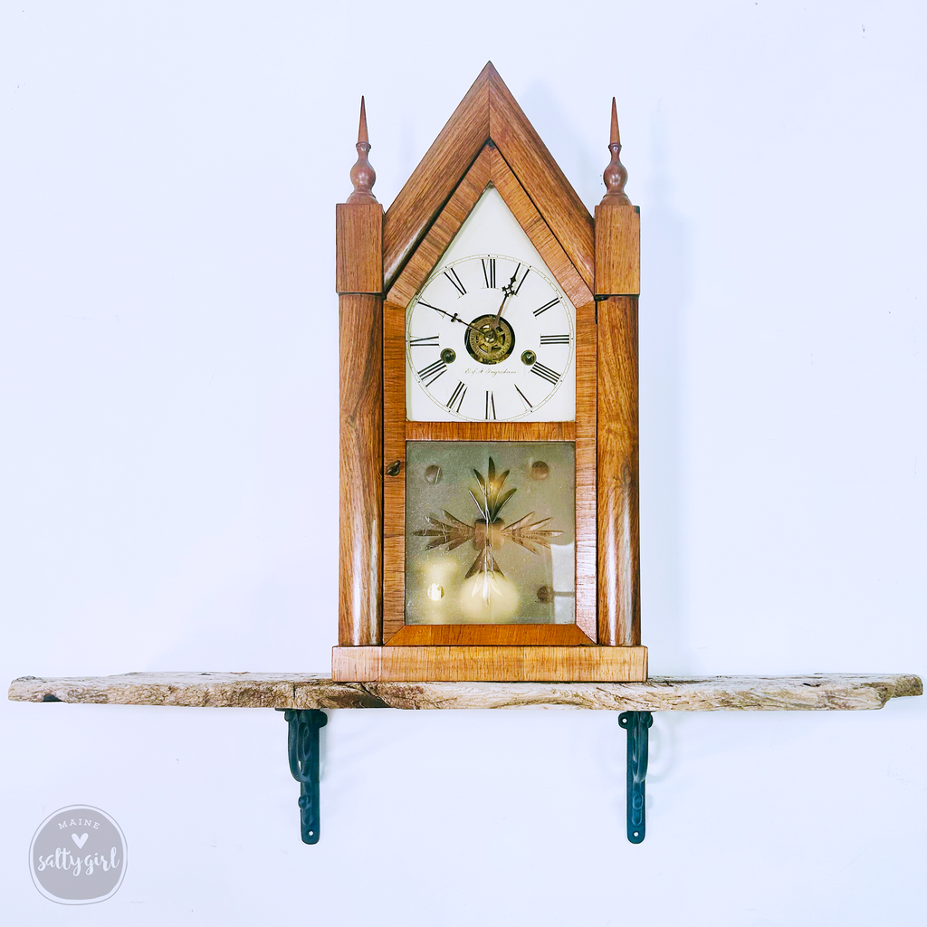 a small wooden clock on a shelf on a wall