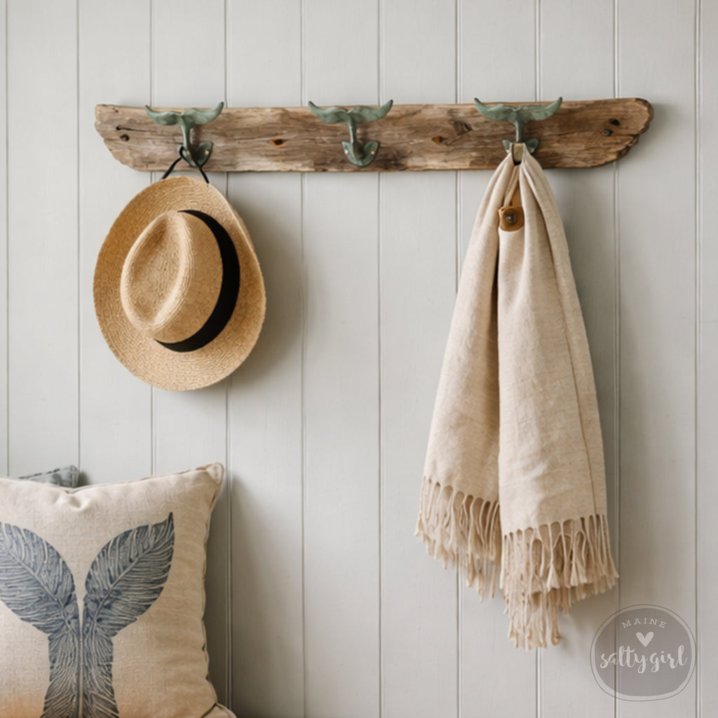 a rustic wooden coat rack with three hooks, displaying a hat, a scarf, and a pillow.