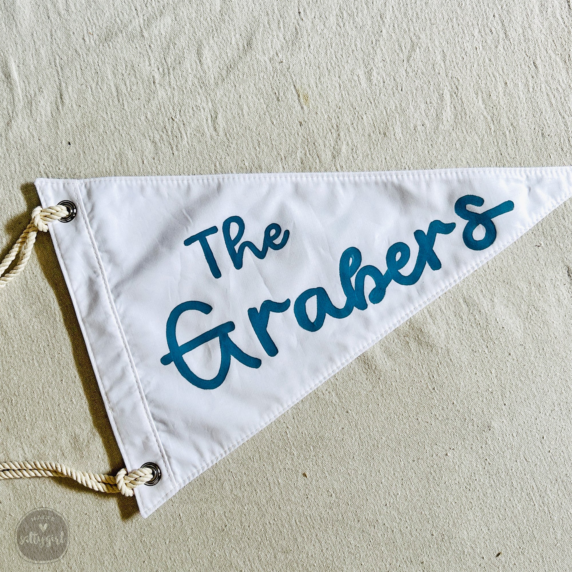 White triangle flag with 'The Grabbers' in blue text on a beige background