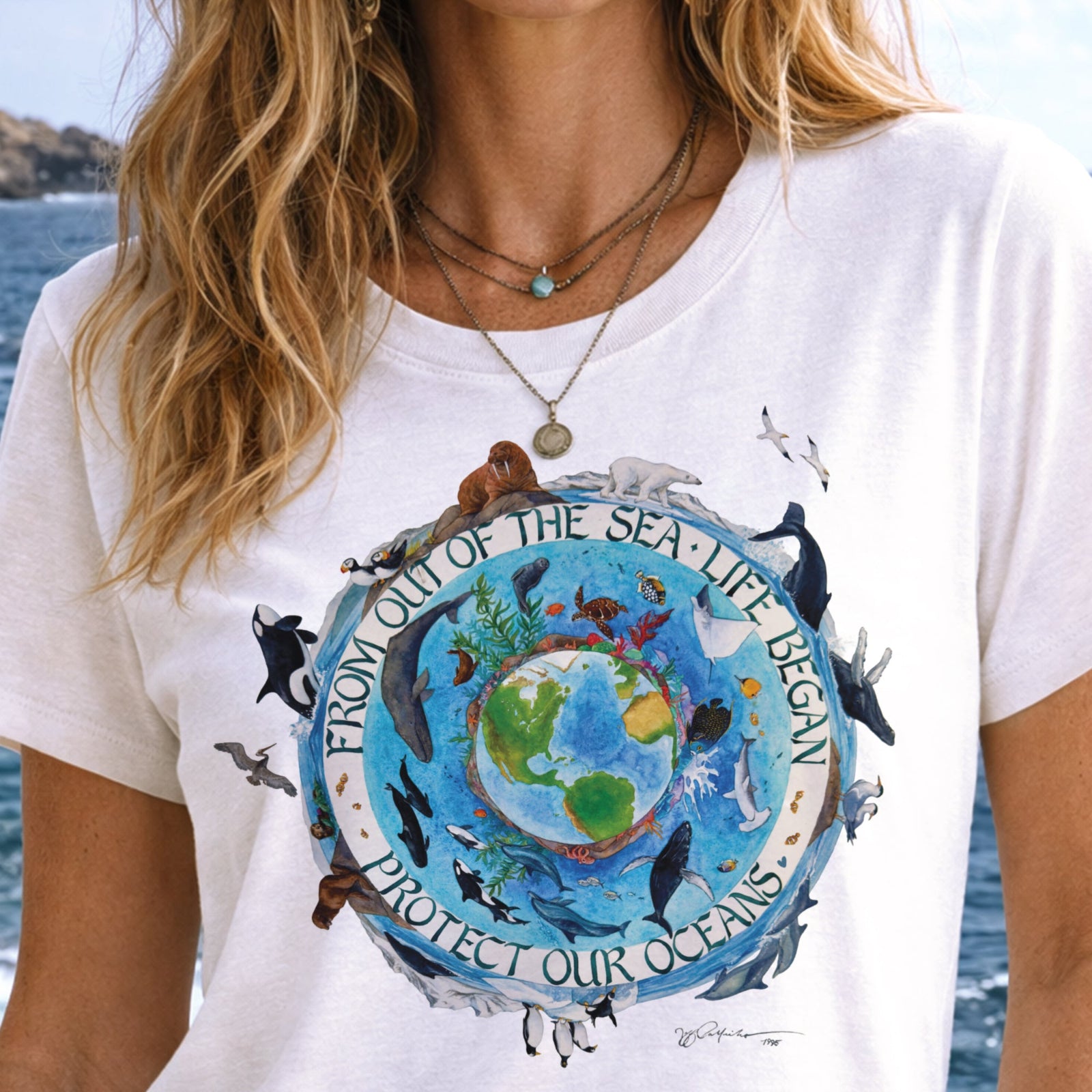 Person wearing a white t-shirt with an ocean-themed graphic and text.