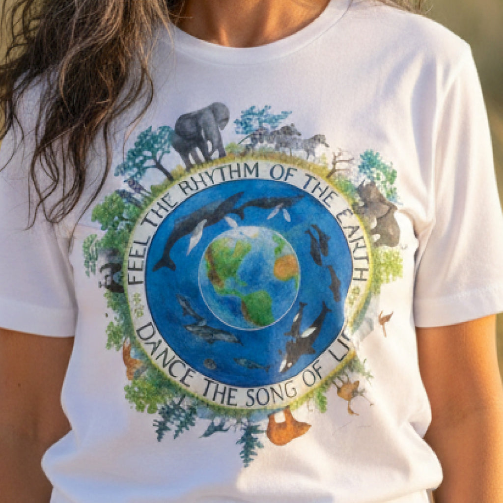 A white Maine Salty Girl t-shirt with a circular design featuring a blue globe surrounded by various animals and text, including the phrase "Feel the rhythm of the earth, dance the song of life".