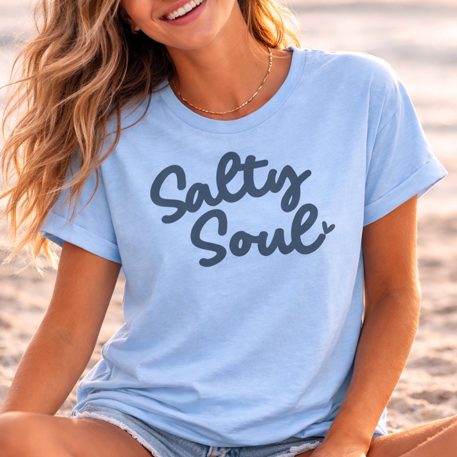 Person wearing a light blue t-shirt with 'Salty Soul' text on a beach.