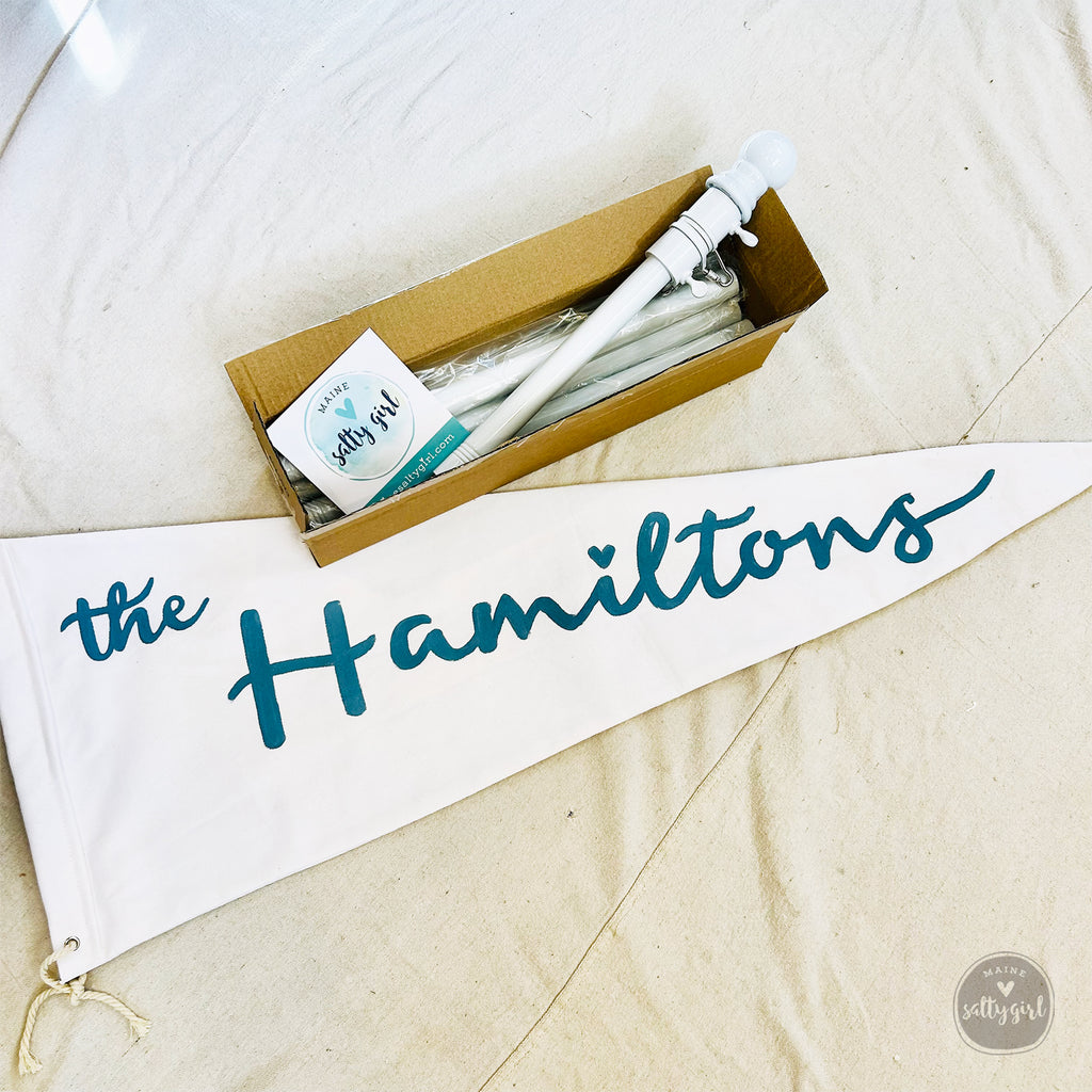 Flag pole in a box with a 'the Hamiltons' banner on a beige surface