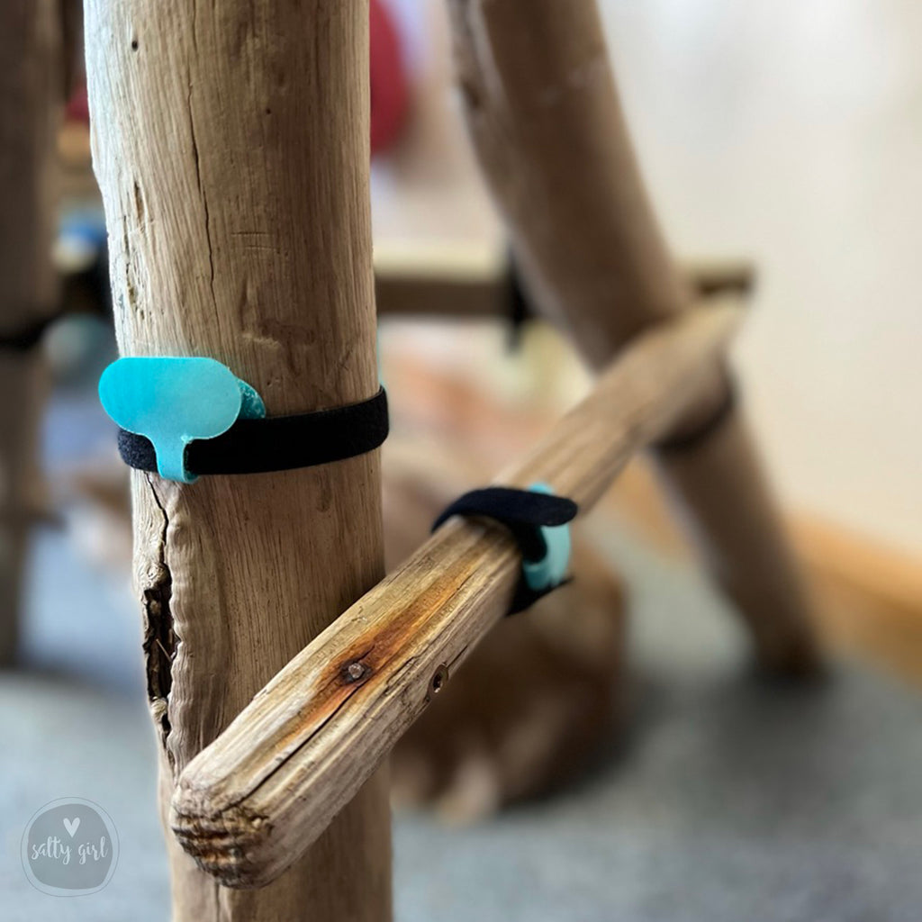 A wooden post with a blue rubber band attached to it, and another wooden post with a blue rubber band attached to it, both placed on a wooden surface.