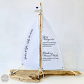 A white sailboat-shaped object made of driftwood, displaying a menu of alcoholic beverages.