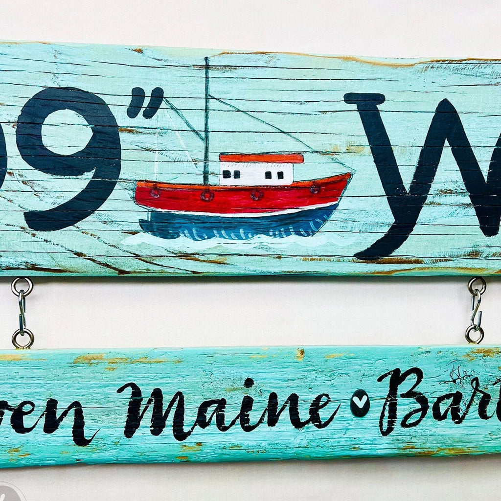 A wooden sign with a painted image of a boat and the text "9 W" on it.