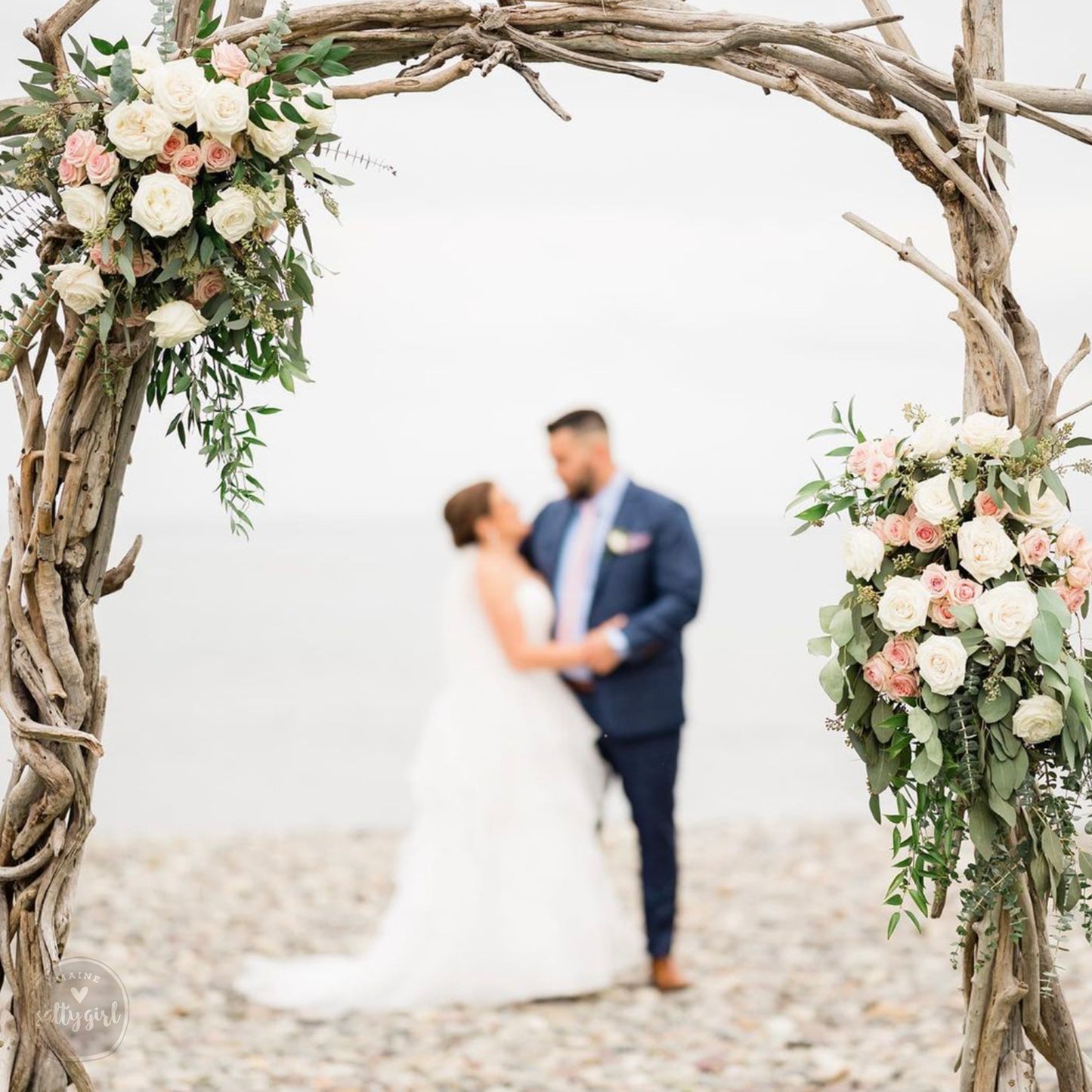 a bride and groom standing under a wooden arch