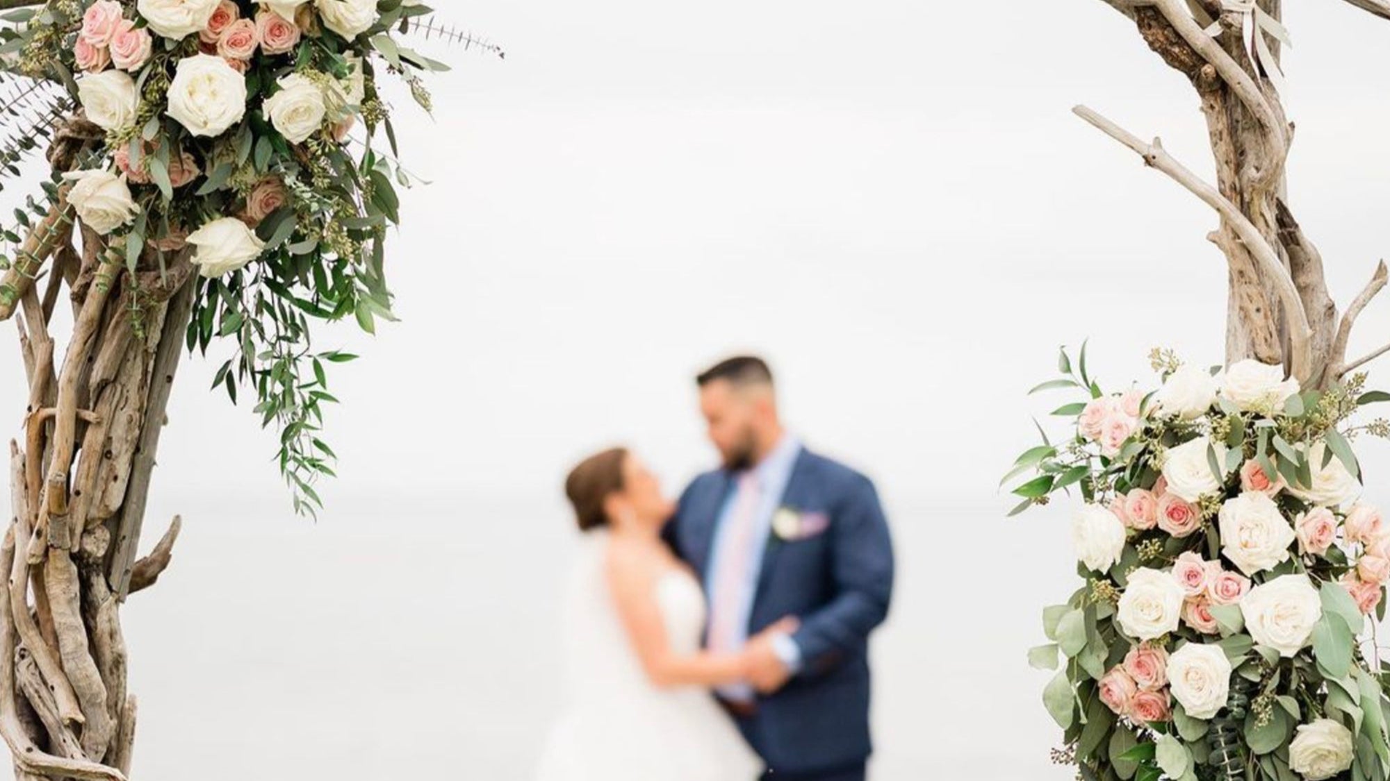 a bride and groom standing under a wooden arch