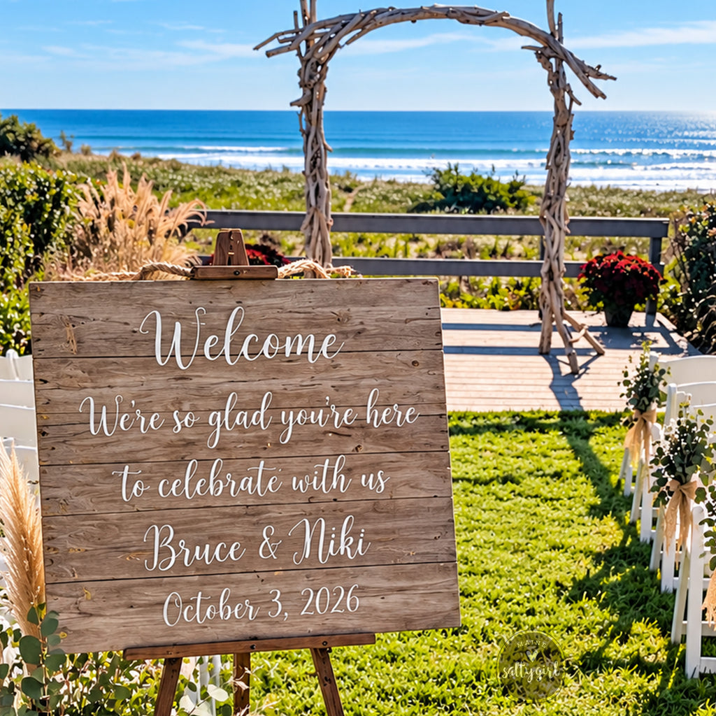 a wooden sign welcoming guests to a wedding ceremony, with a scenic view of the ocean in the background.
