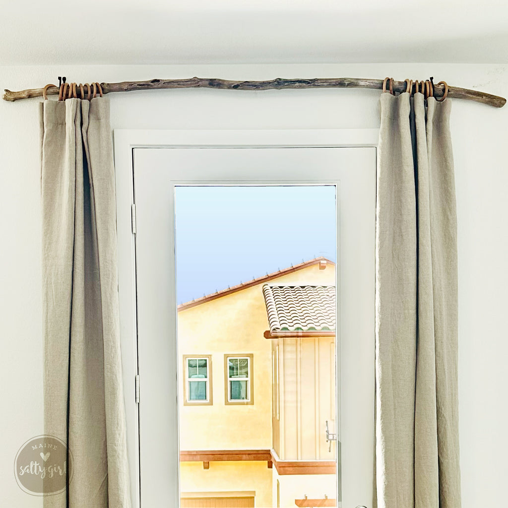 a view from a window, with a wooden branch hanging from the ceiling and a yellow building visible through the window.