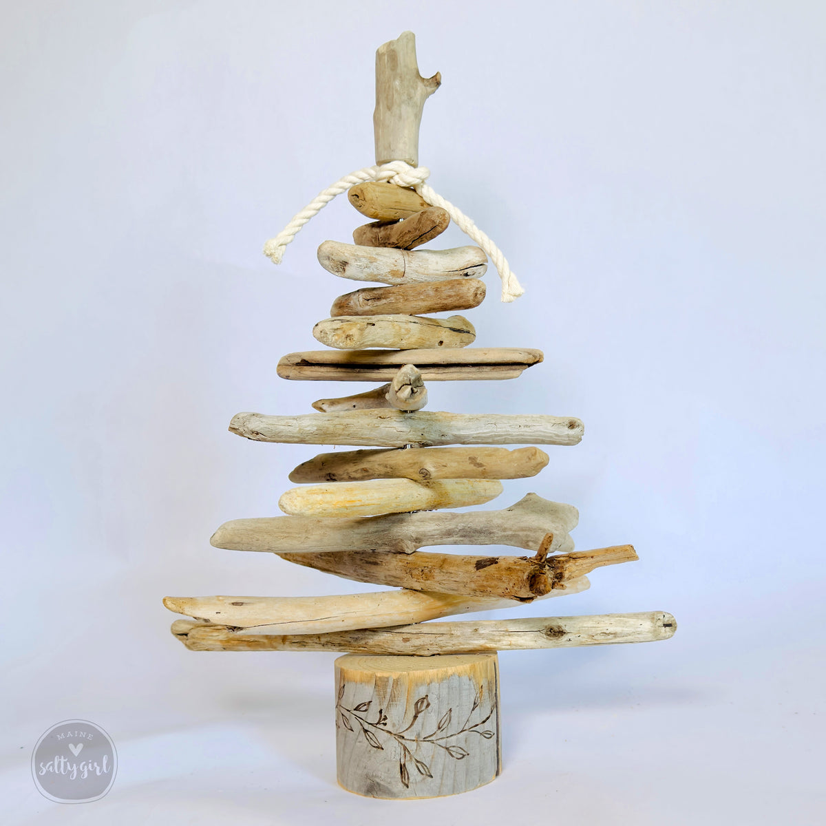 A creative arrangement of driftwood pieces forming a tree-like structure, with a rope tied around the top piece.