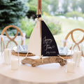A table setting with a decorative sailboat centerpiece, featuring the names 'Jenny & Tim' and the date 'July 18, 2020'.