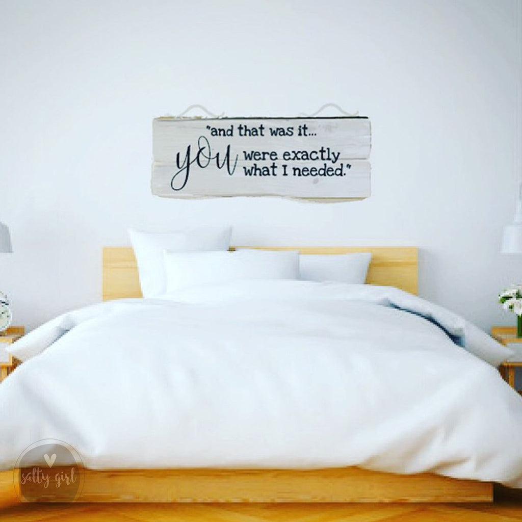 a bedroom with a bed and a wooden headboard. Above the bed, there is a sign with a message that reads "and that was it... you were exactly what I needed."