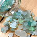 a jar filled with sea glass on top of a wooden table