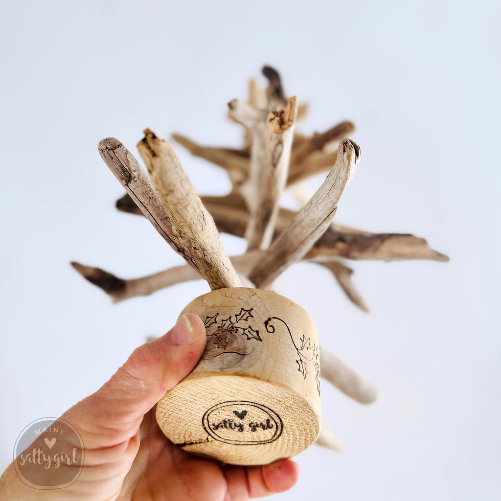 A hand is holding a wooden object with a design on it, which appears to be a decorative piece.