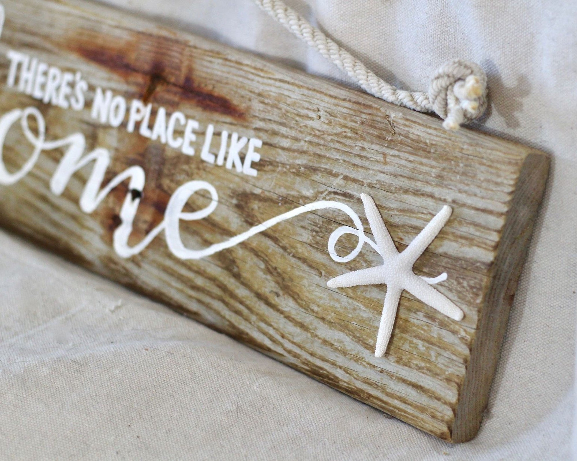 A wooden sign with the text "There's no place like home" written on it, along with a starfish decoration.
