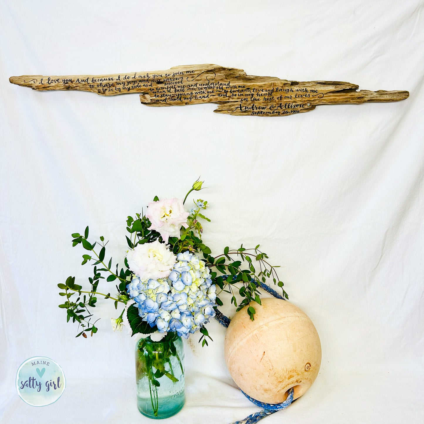 a vase filled with flowers next to a wooden sign