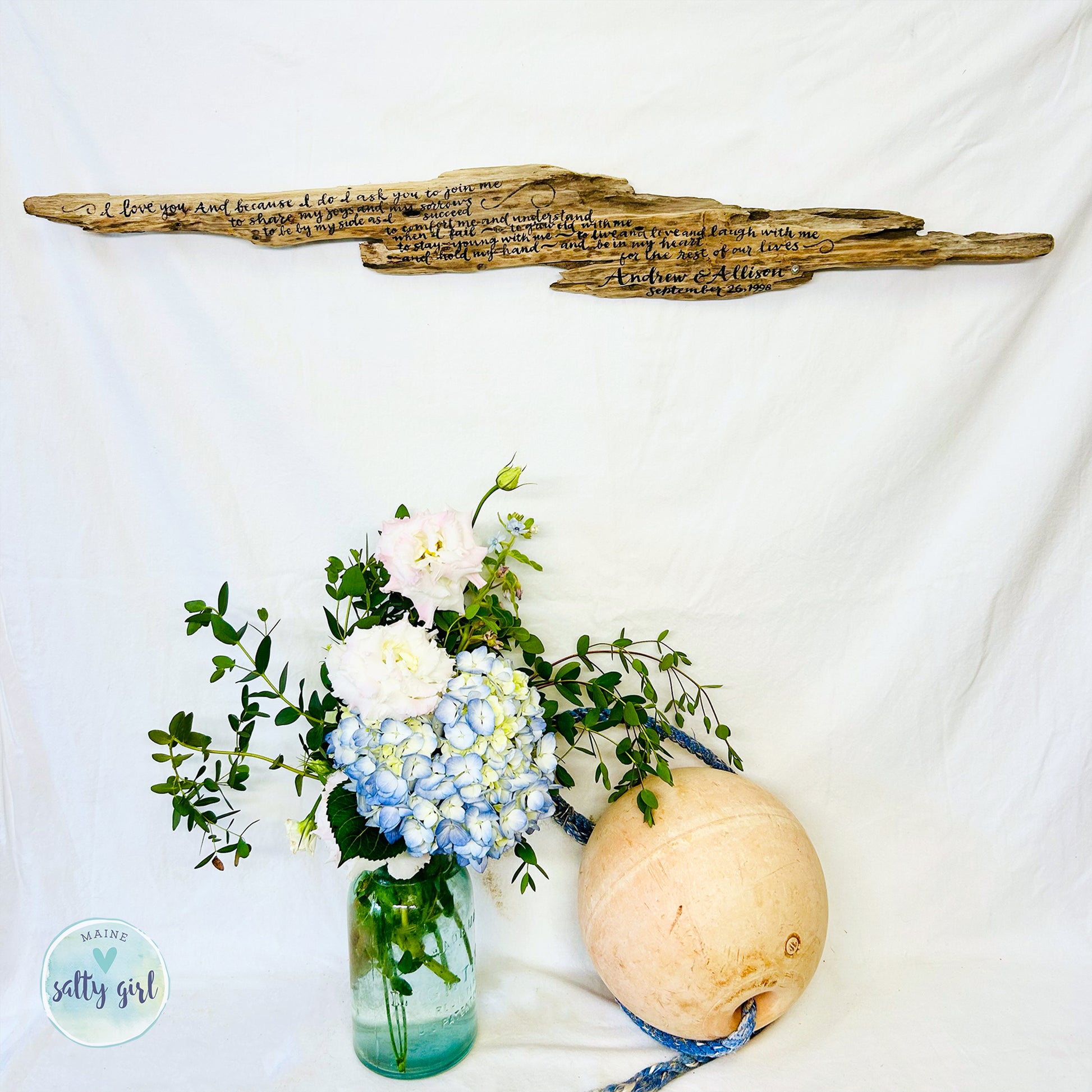 a vase filled with flowers next to a wooden sign