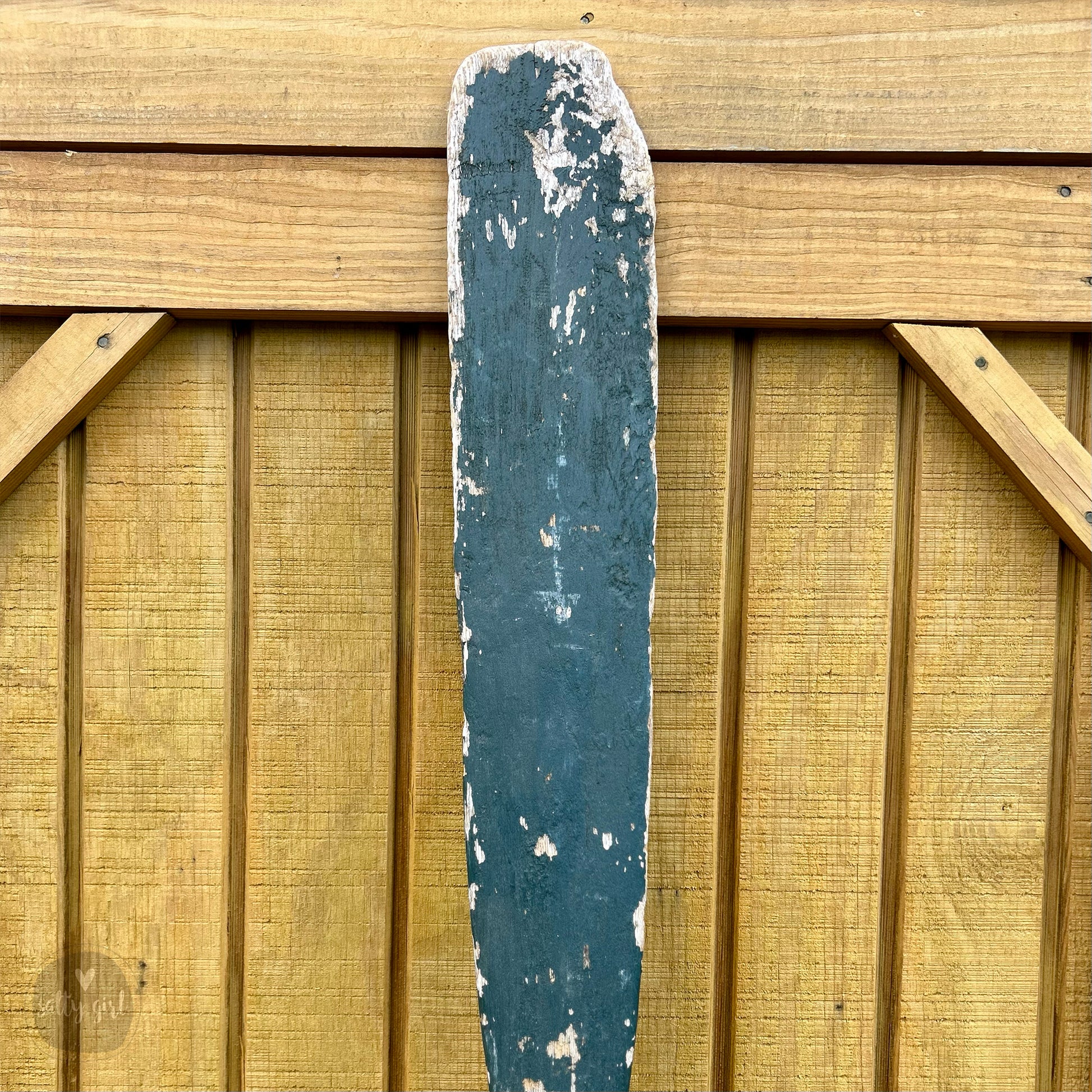 a blue and white surfboard sitting on top of a wooden wall