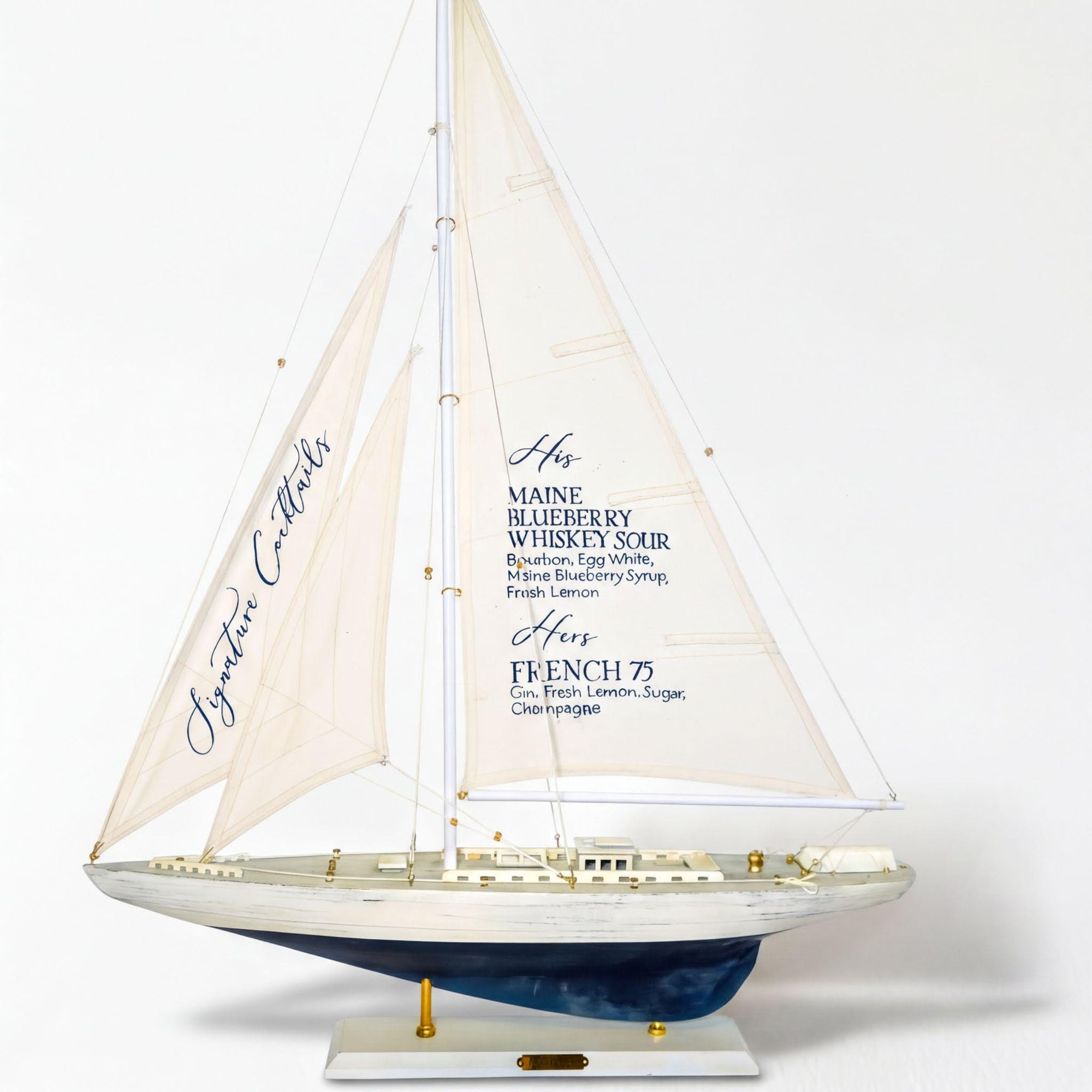 A model of a sailboat with a white sail and blue hull, featuring text on the sail that lists various alcoholic beverages.