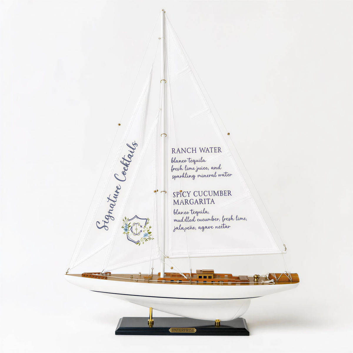 A model of a sailboat with a menu displayed on its sail, featuring various cocktail recipes.