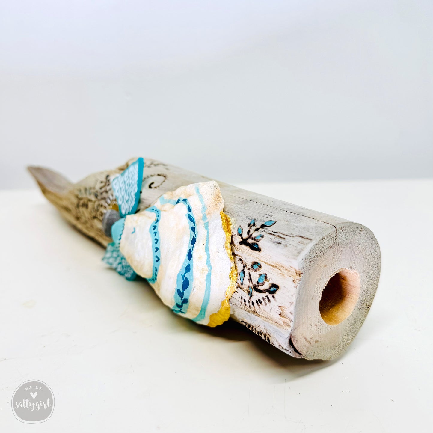 A wooden sculpture with a carved design and a hole in the center, sitting on a white surface.