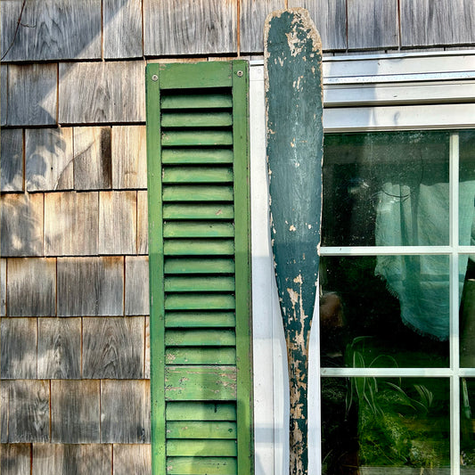 a window with green shutters and a green curtain