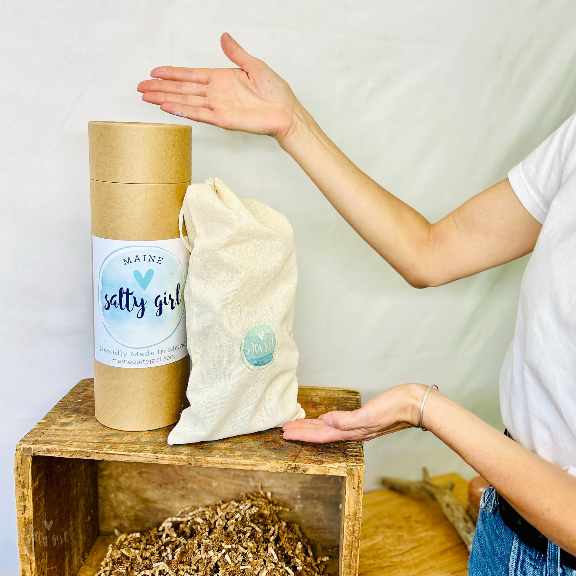 A Maine Salty Gilr miniature driftwood tree inside a storage tote with a kraft canister