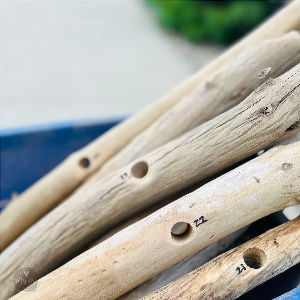 A close-up image of several wooden sticks or branches with holes in them, arranged in a pile.