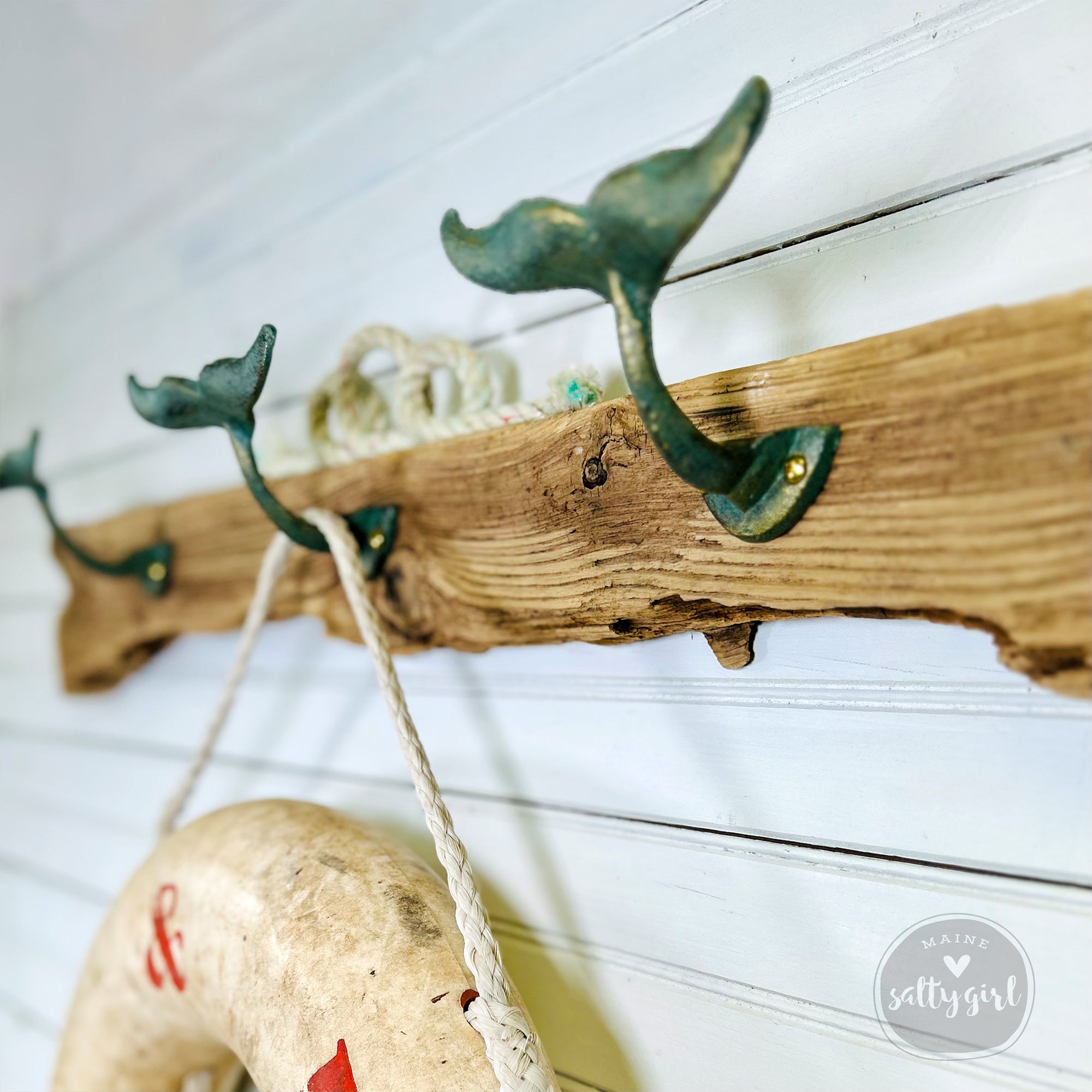a wooden shelf with a green metal hook on it, and a white life preserver hanging on the wall below it.