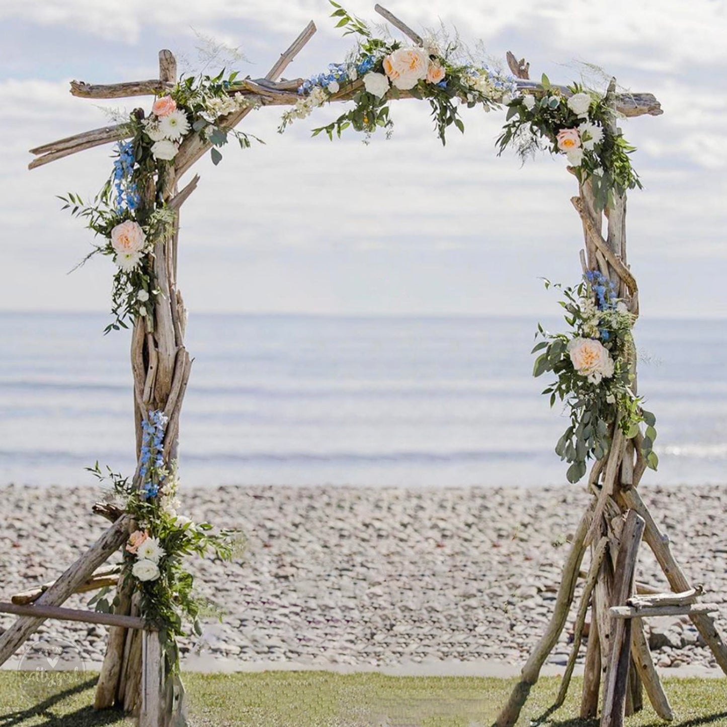 a wooden arch decorated with flowers on the beach