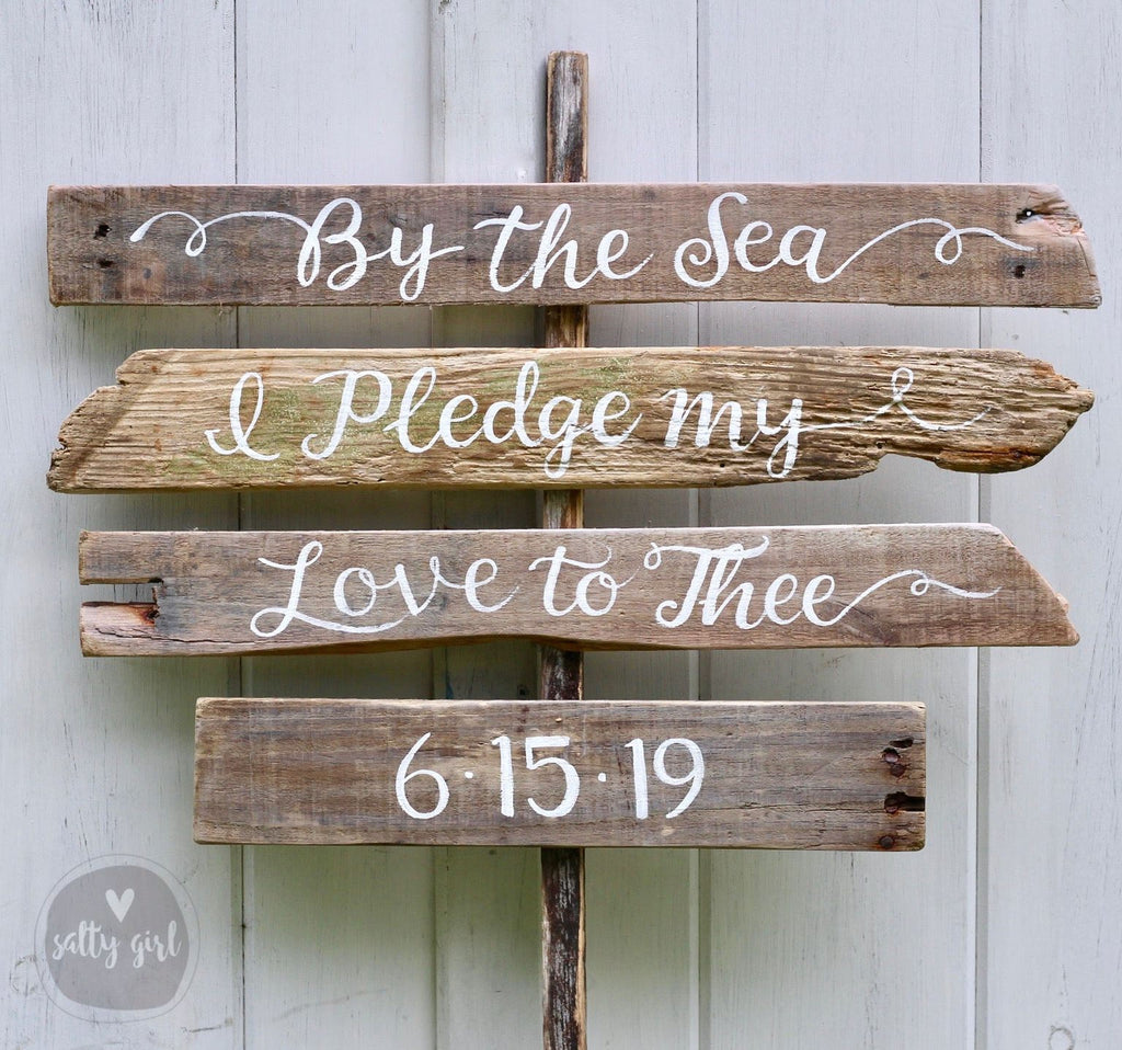 A wooden sign with the text "By the Sea Ipled my Love to Thee 6:15:19" written on it.