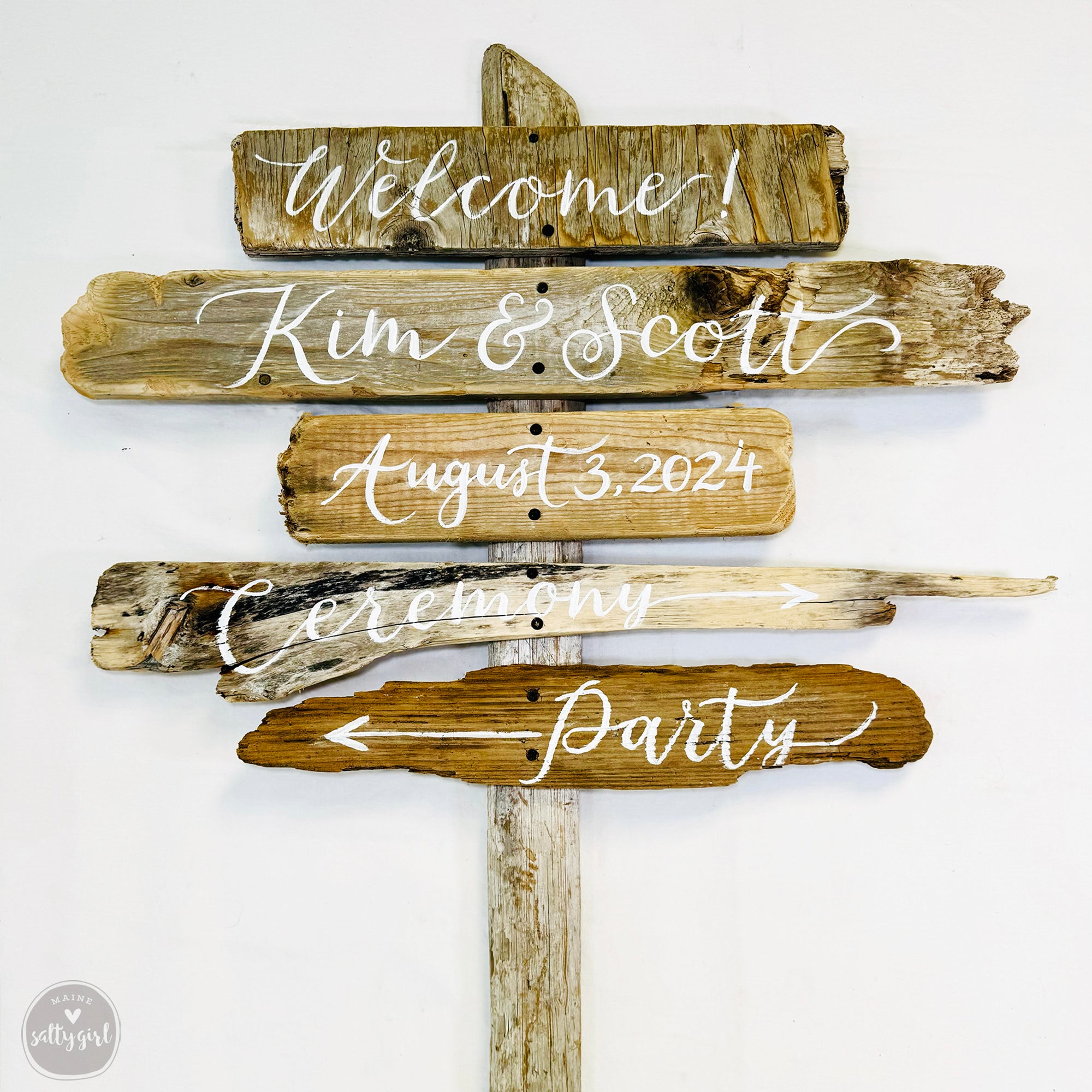 a wooden sign with various directional signs attached to it, including a welcome sign, a date sign, and a party sign.