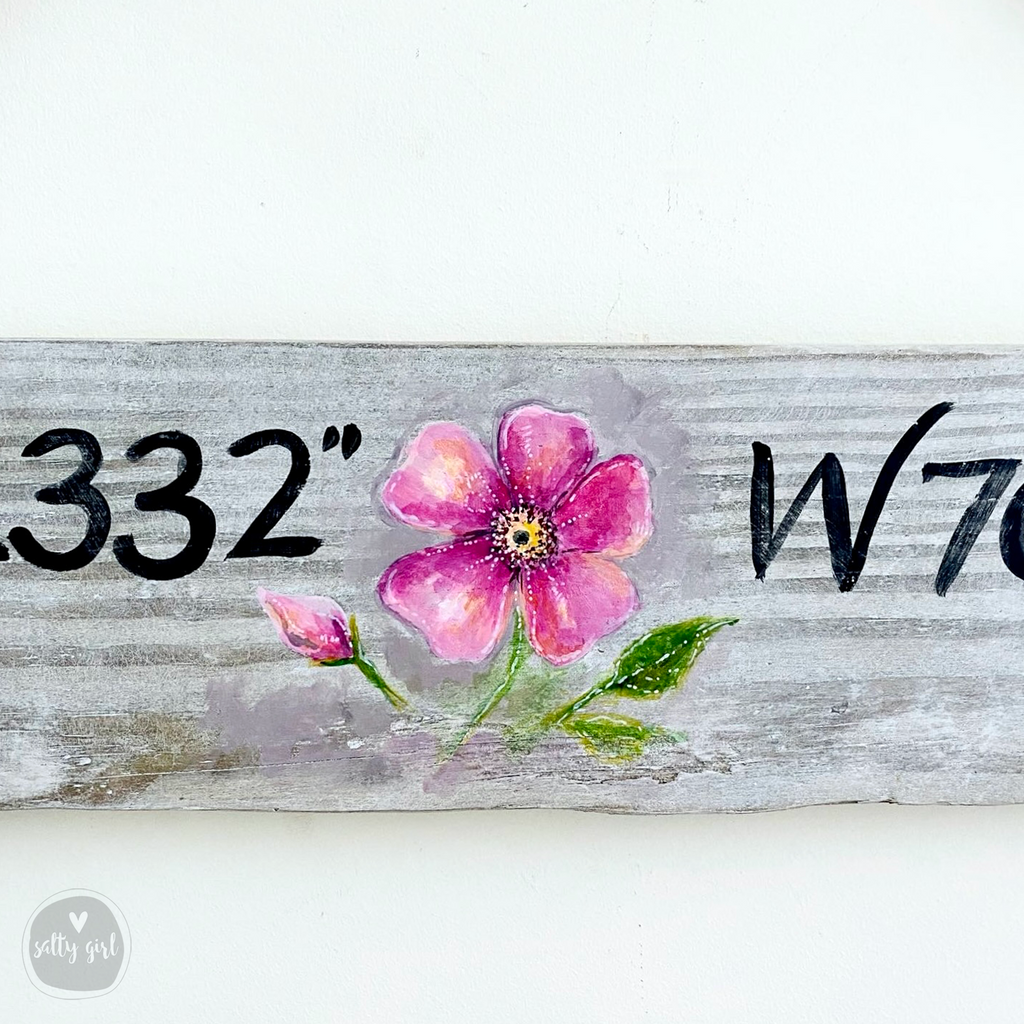a wooden sign with a flower painted on it