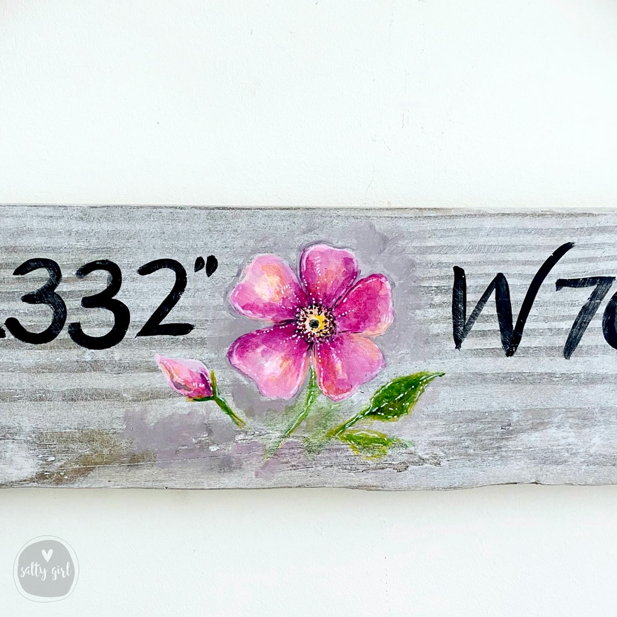 a wooden sign with a flower painted on it