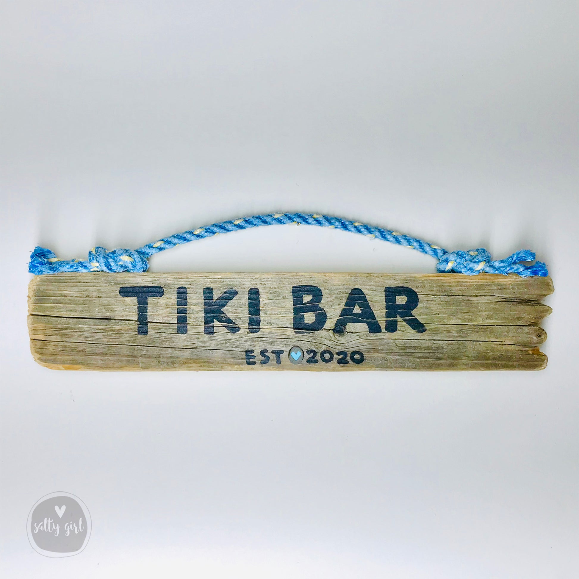 A wooden sign with the text "Tiki Bar" and "EST. 2020" printed on it, along with a blue rope handle.