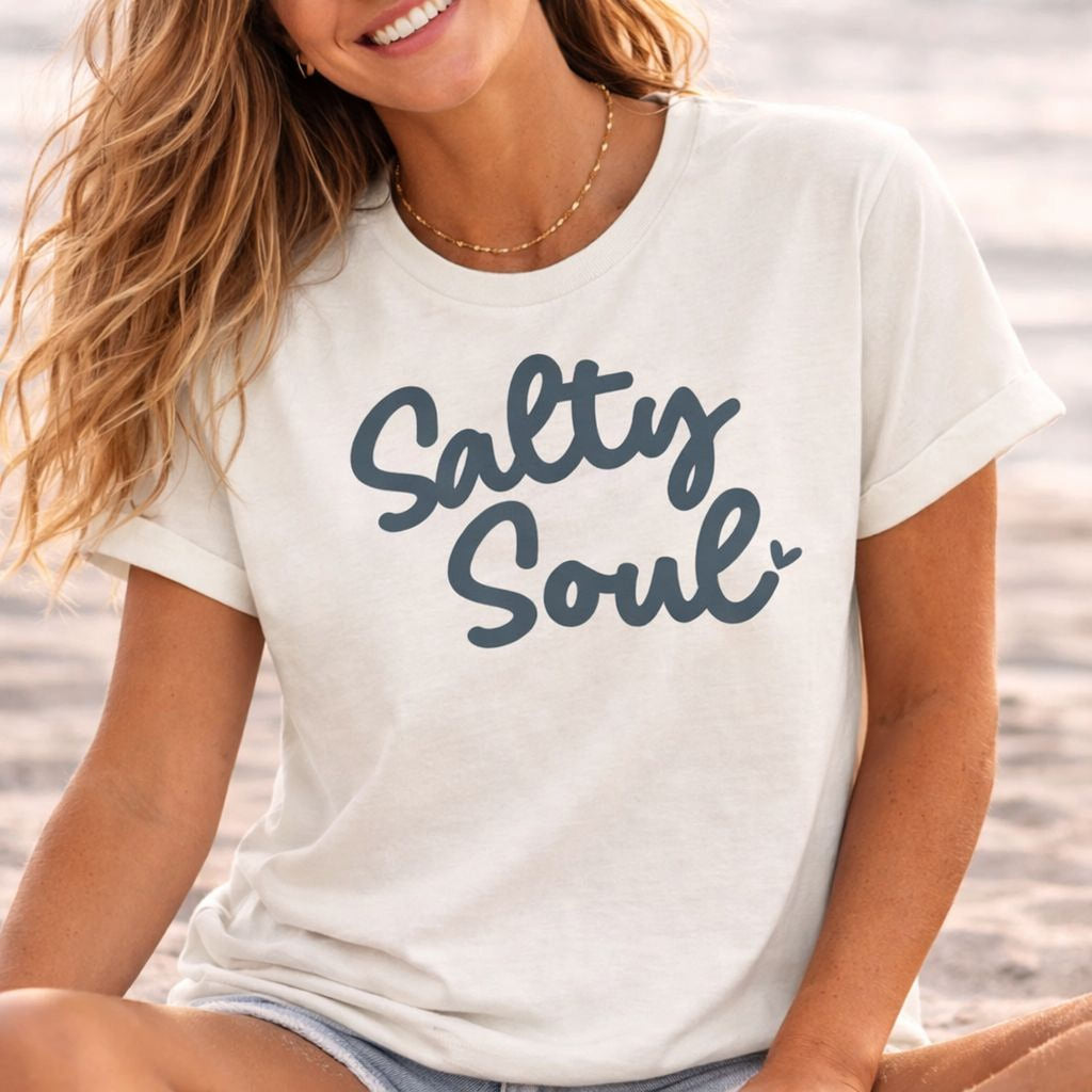 Woman wearing a vintage white t-shirt with 'Salty Soul' text on a beach.