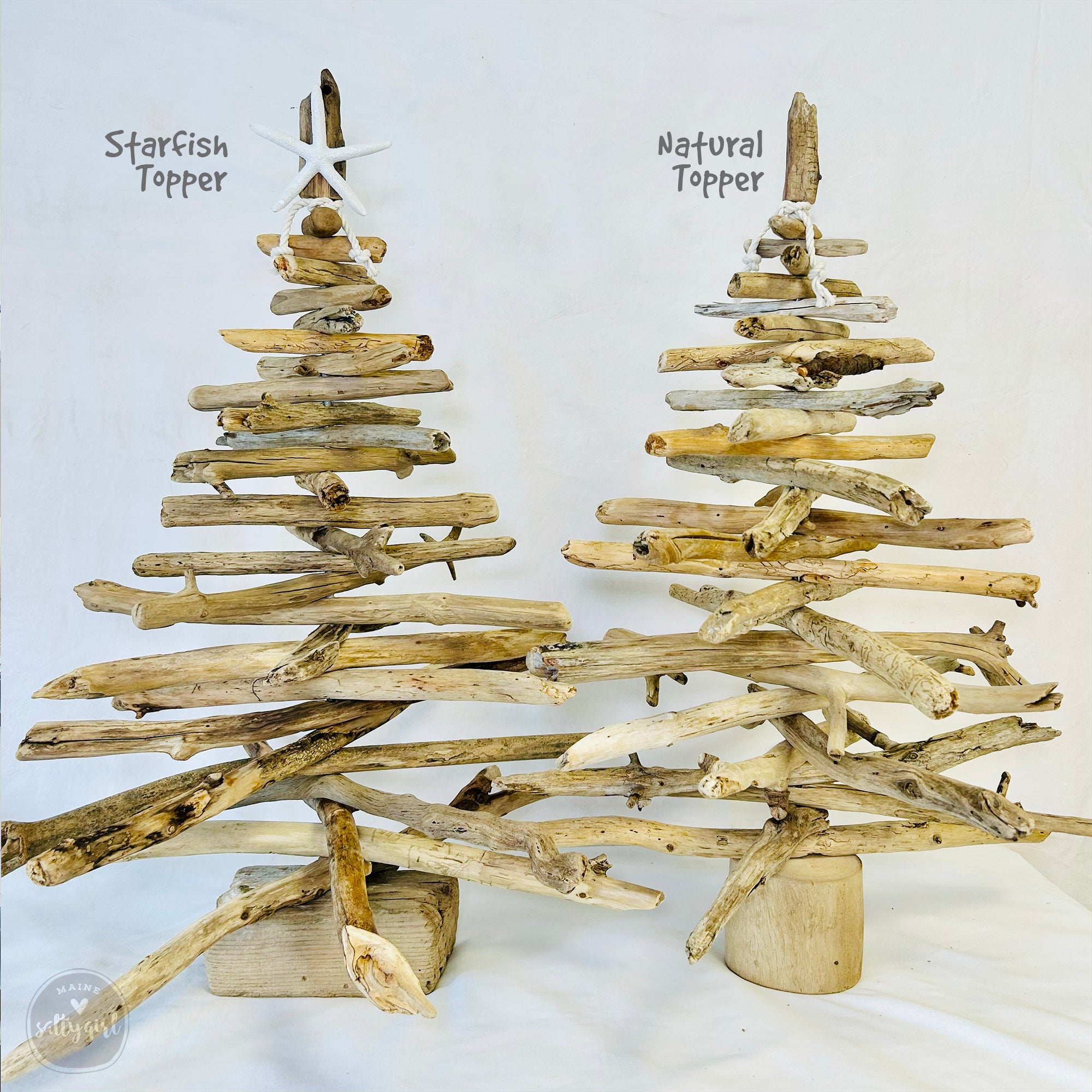 Two driftwood Christmas trees made from various branches and twigs, with starfish and natural topper decorations.