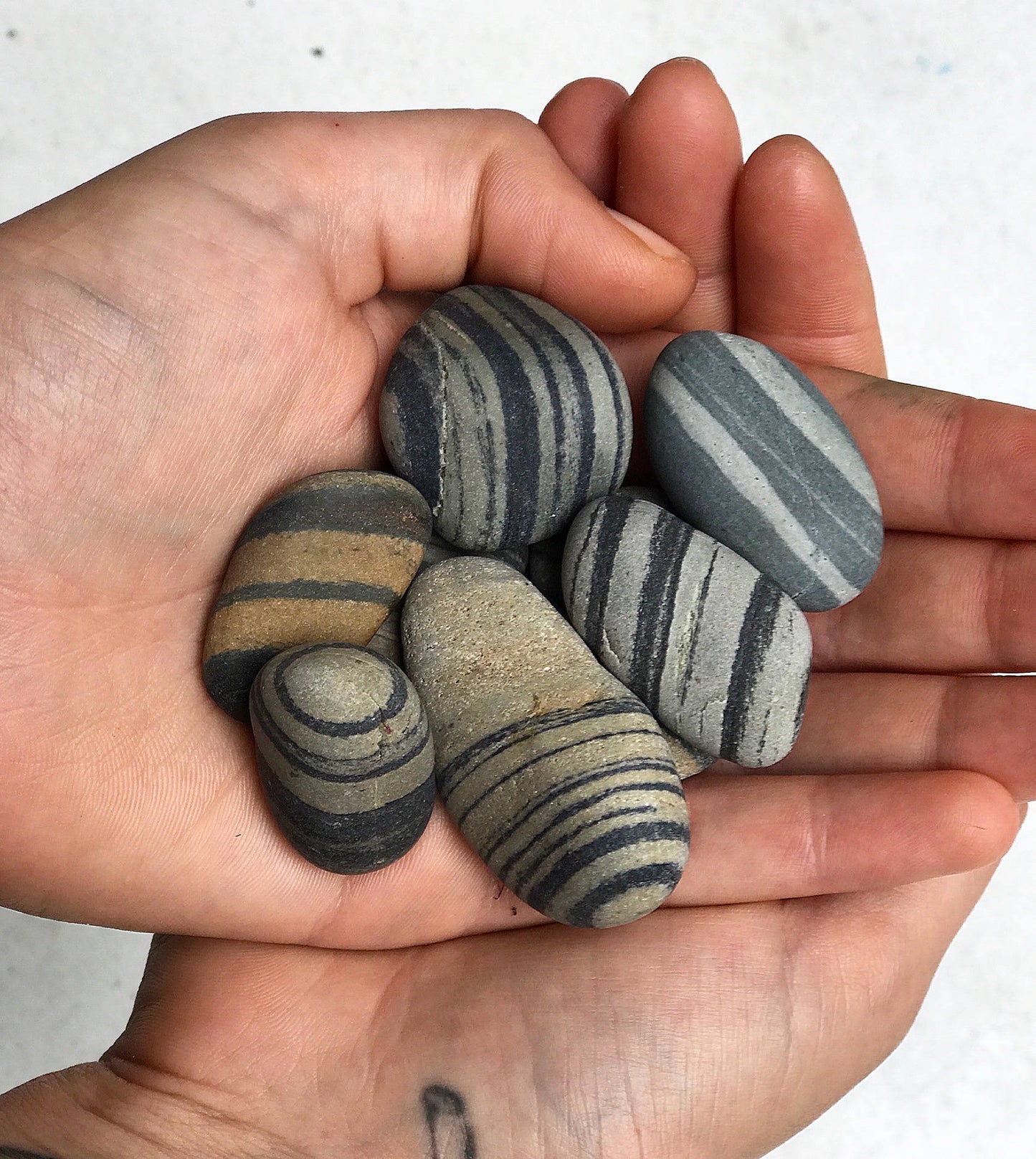 Hands holding small striped beach stones