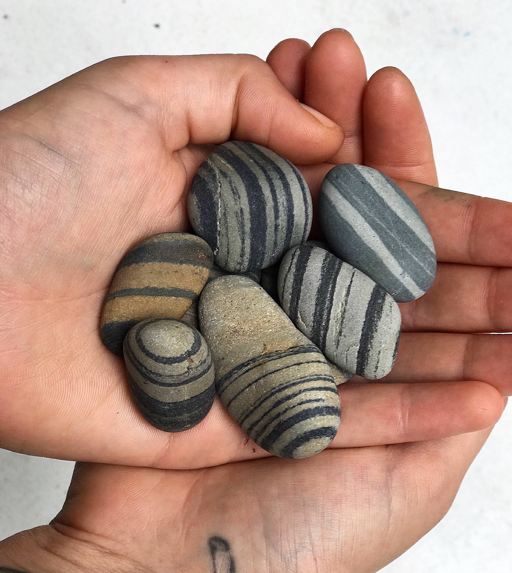 Hands holding small striped beach stones