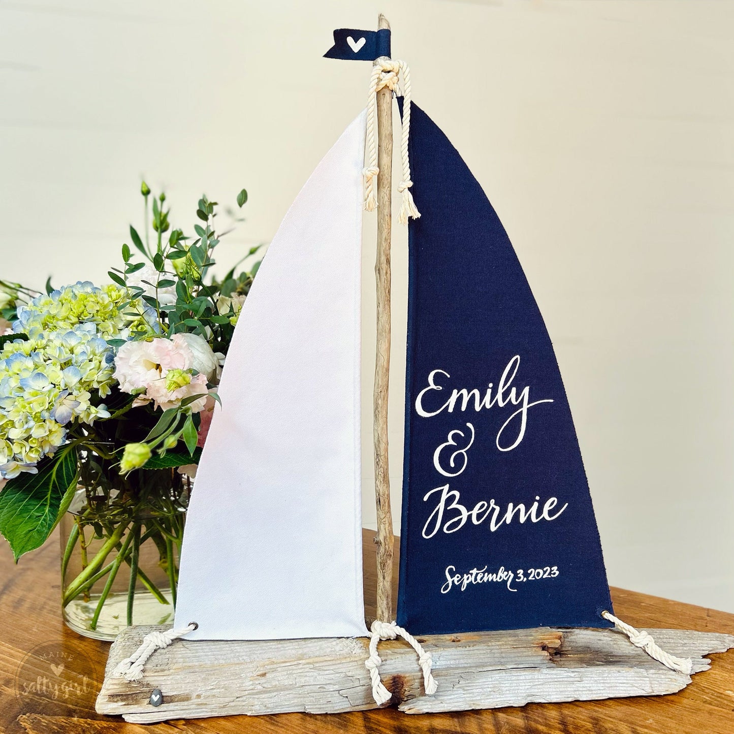 a sailboat is sitting on a table next to a vase of flowers