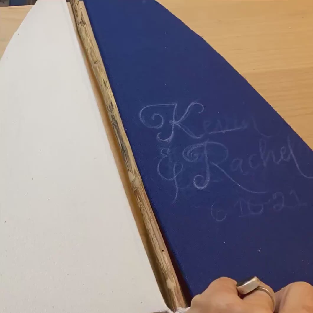 Hand lettering sails on driftwood sailboat