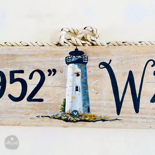 a wooden sign with a lighthouse painted on it.